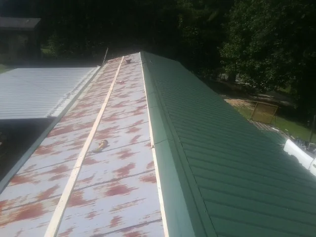 Old rusted panels beside newly installed green metal roofing — Wind Damage Roof Repair by Roofing Brothers in Chappaqua