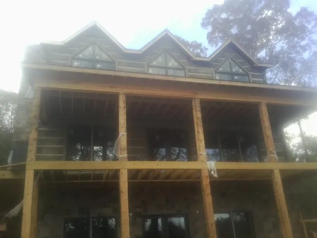 Dormers and porch framing on a large log home under construction — Roof Coating work by our crew in Chappaqua