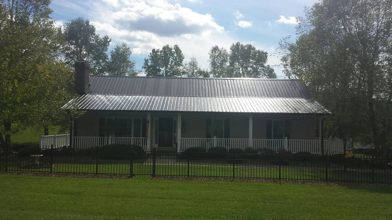 Gray metal roof on a brick ranch with a full width front porch — Gutter Guard Installation work by our crew in Chappaqua