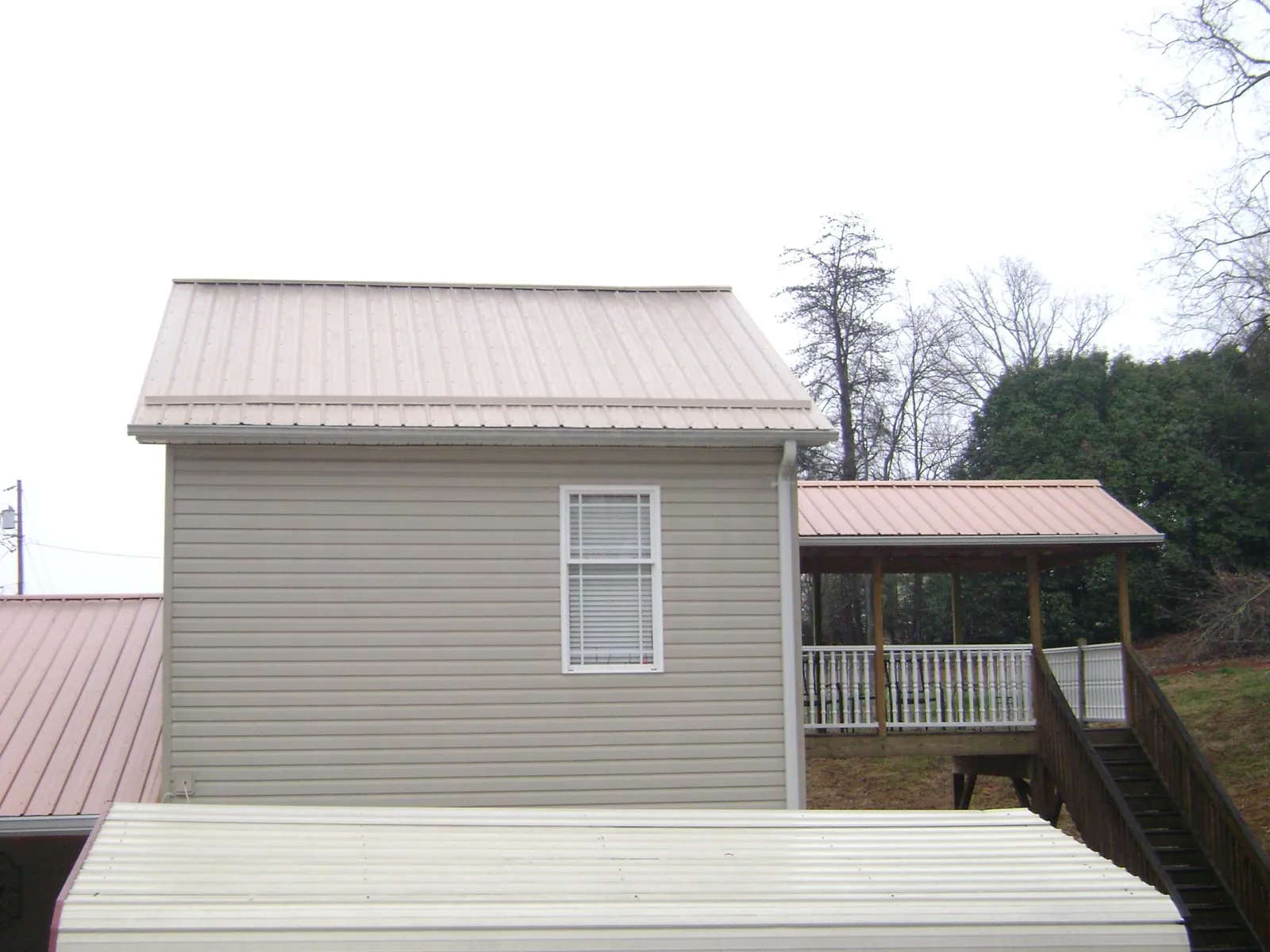 Tan metal roofs on a two story addition and attached porch, from a Roof Replacement job in Chappaqua
