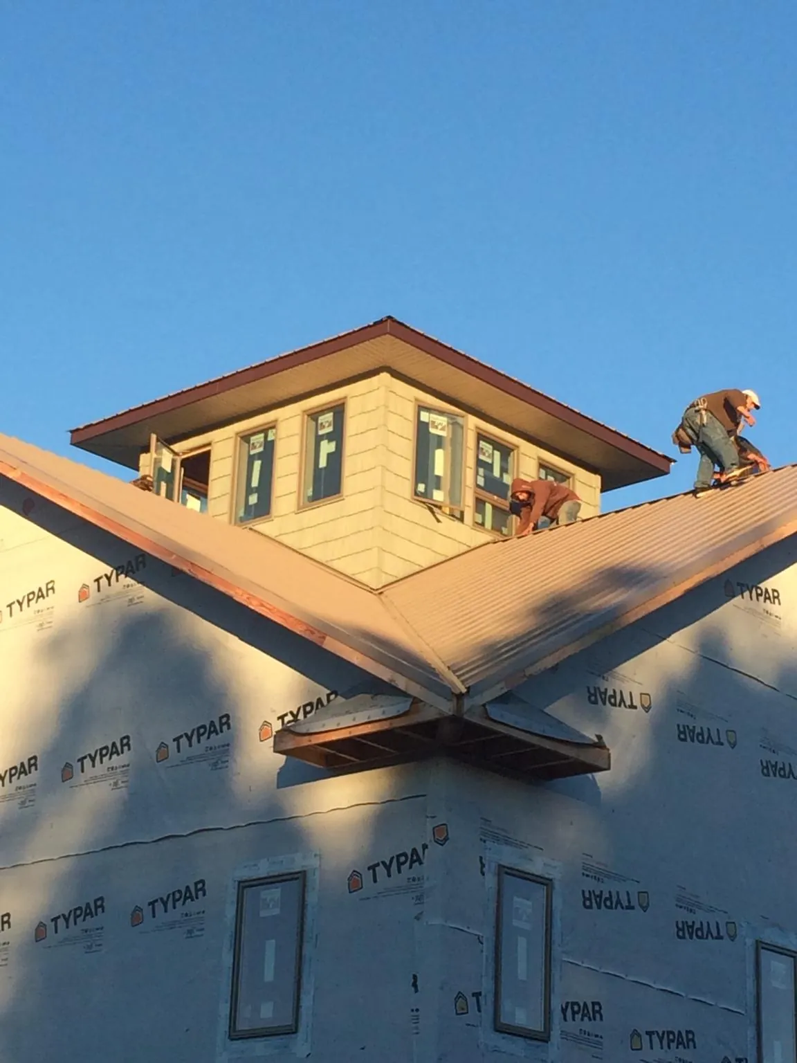 Roofers working around a rooftop cupola on a new metal roof at sunset — Roof Waterproofing in Chappaqua by Roofing Brothers